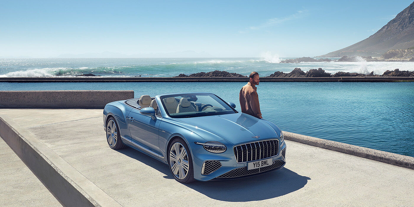 Bentley Melbourne New Bentley Continental GTC Azure convertible front view in Light Windsor blue paint with 22 inch ten spoke wheels parked by the sea in the sunshine