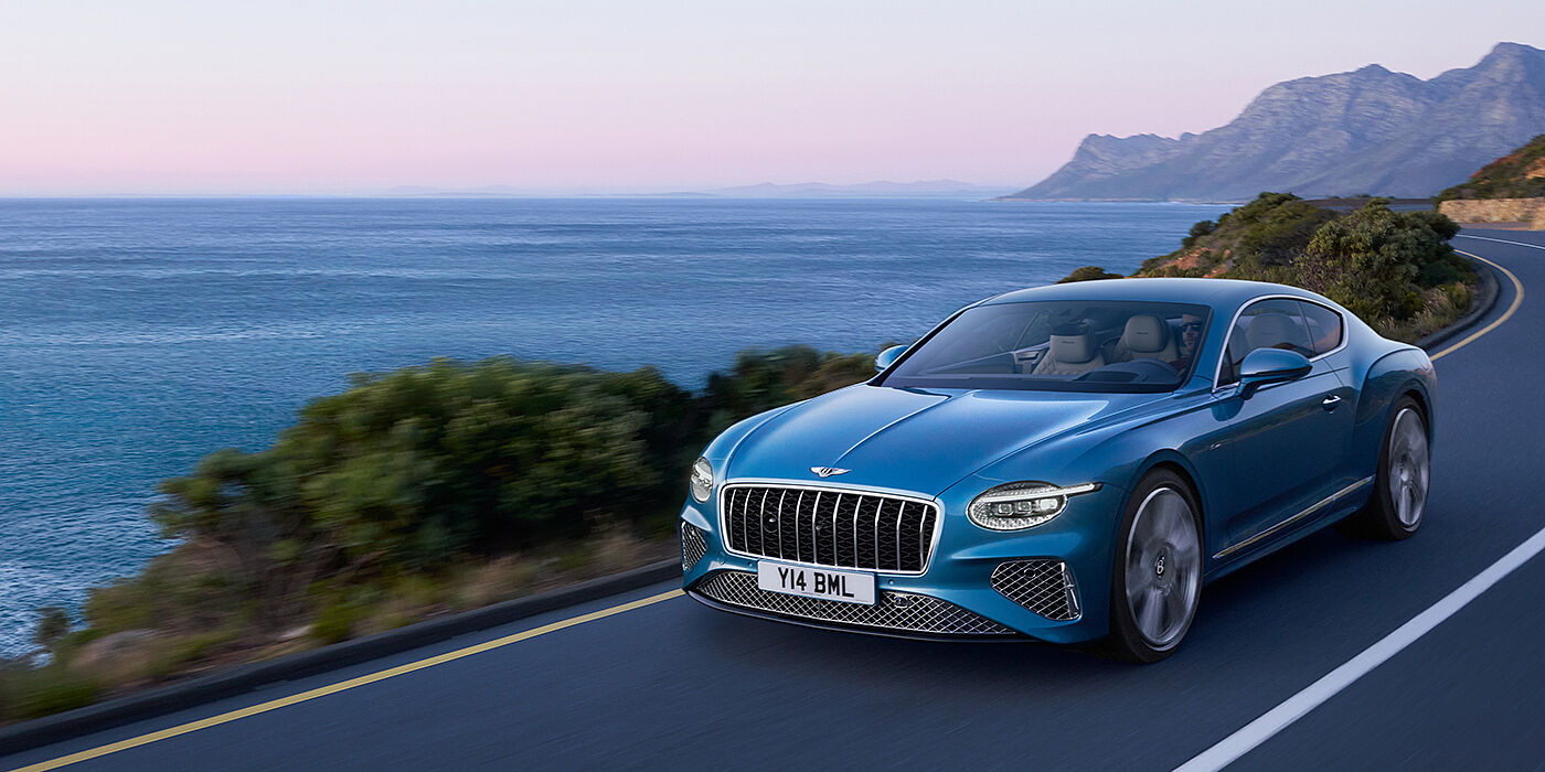 Bentley Melbourne New Bentley Continental GT Azure coupe in Light Windsor blue paint with 22 inch Azure wheels and chrome grill, driving dynamically by the sea