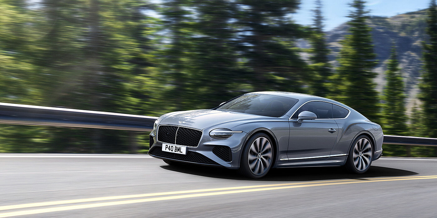 Bentley Melbourne New Bentley Continental GT coupe in Silverlake paint and 22 inch ten-spoke wheels, driving dynamically on a tree-lined road in the sunshine