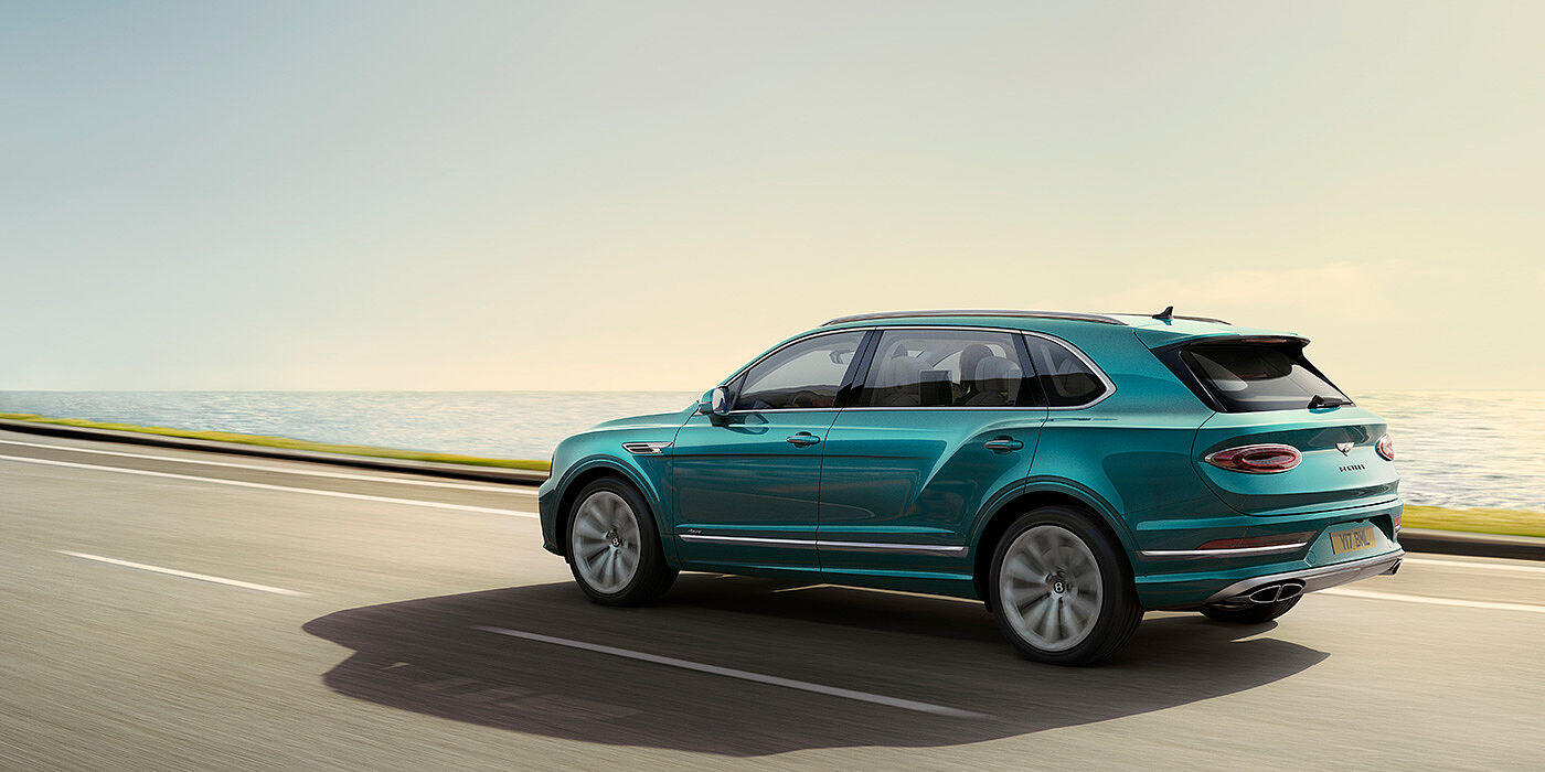 Bentley Melbourne Rear view of a Topaz blue Bentley Bentayga EWB Azure, cruising along a sea side road.