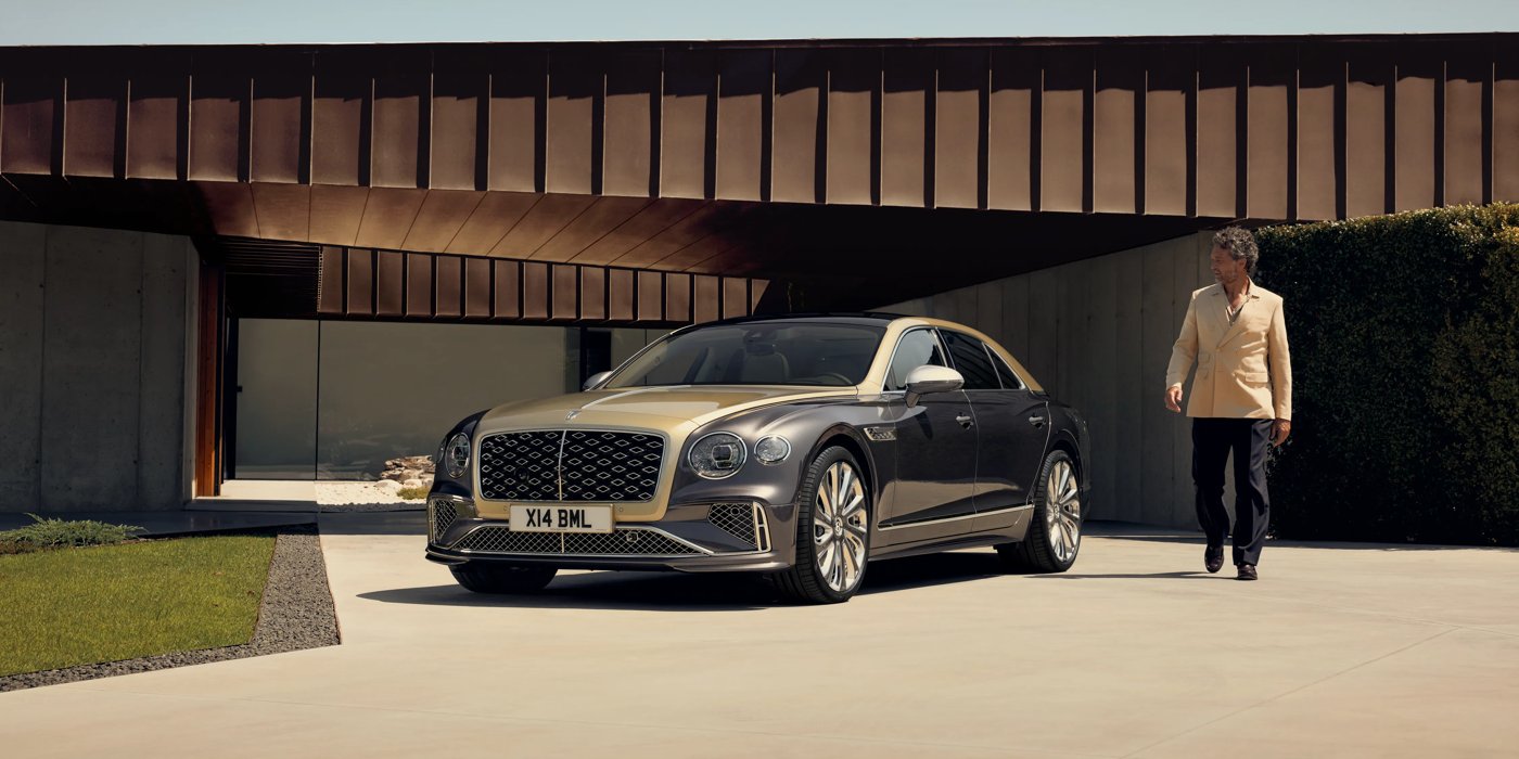 Bentley Melbourne Bentley New Flying Spur Mulliner V8 hybrid sedan front three quarters in Rose Gold over Magnetic paint, parked near modern home