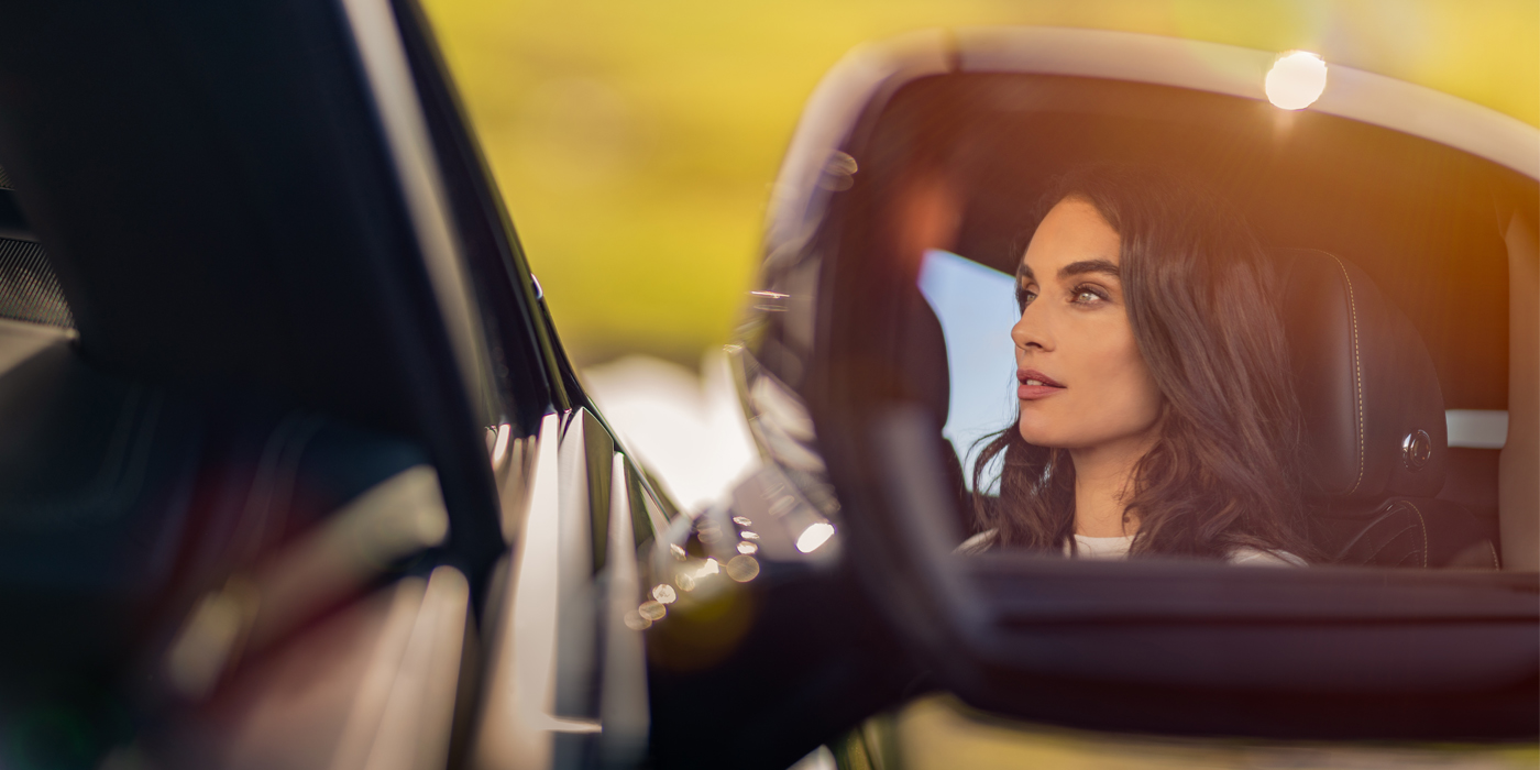 Bentley Melbourne profile of dark haired woman's face in mirror of Bentley car in sunlight