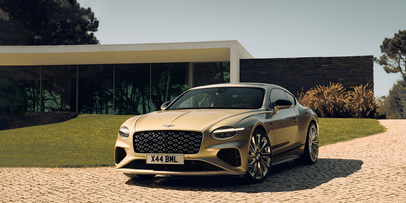 Bentley Melbourne Bentley Continental GT Mulliner coupe front three quarters in Patina paint parked outside a glass fronted building with a grass lawn behind it