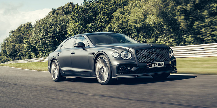 Bentley Melbourne Bentley Flying Spur Mulliner sedan front three quarter in dark grey paint driving dynamically by some trees on a track