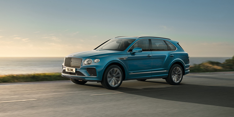 Bentley Melbourne Bentley Bentayga Azure SUV in Topaz blue paint driving dynamically by the ocean with 22 inch 10 spoke directional wheels