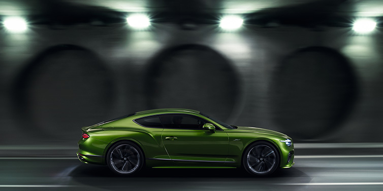 Bentley Melbourne Bentley Continental GT Speed coupe profile in Tourmaline Green driving dynamically past a concrete wall at night