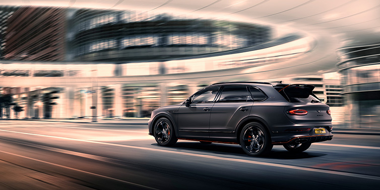 Bentley Melbourne Bentley Bentayga S Black Edition SUV rear three quarter in Anthracite Satin paint driving dynamically through a city at night