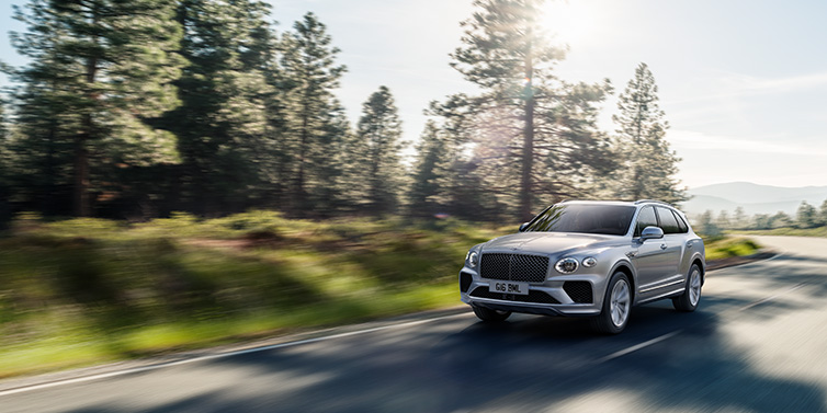 Bentley Melbourne Bentley Bentayga SUV front three quarter in Moonbeam silver paint driving dynamically along a tree-lined road