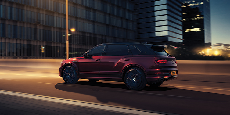 Bentley Melbourne Bentley Bentayga Extended Wheelbase Mulliner SUV in Cricket Ball red paint driving dynamically in city at night